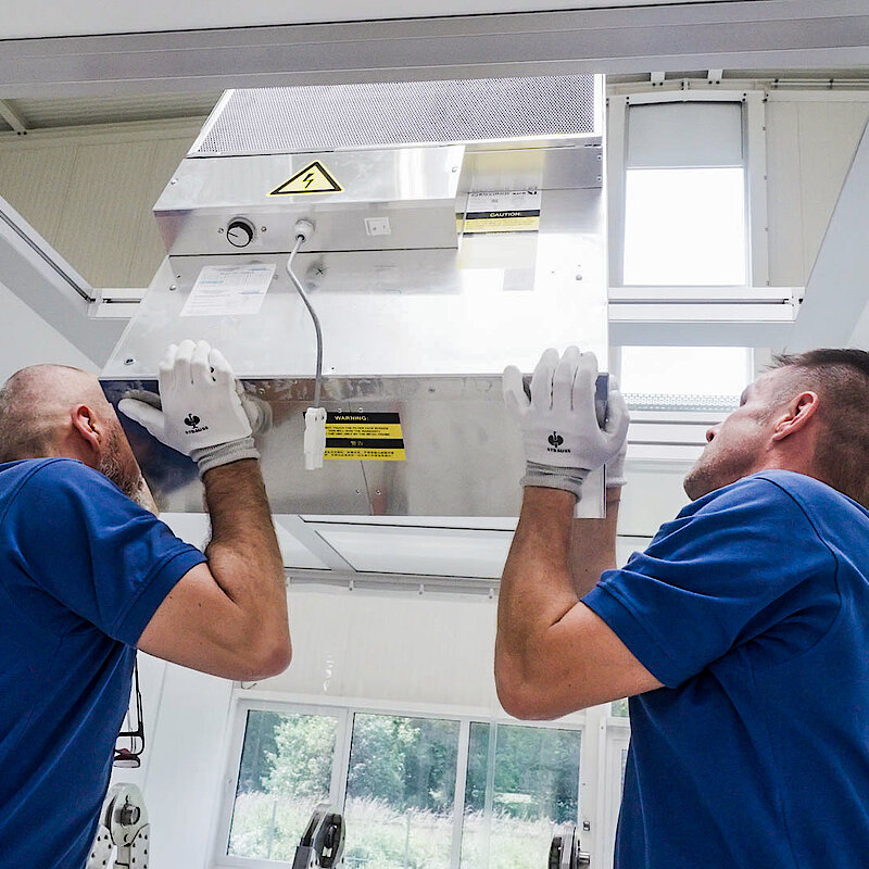 [Translate to English:] Zwei SErvicetechniker in blauen Polos wechseln einen Filter in einem Reinraum