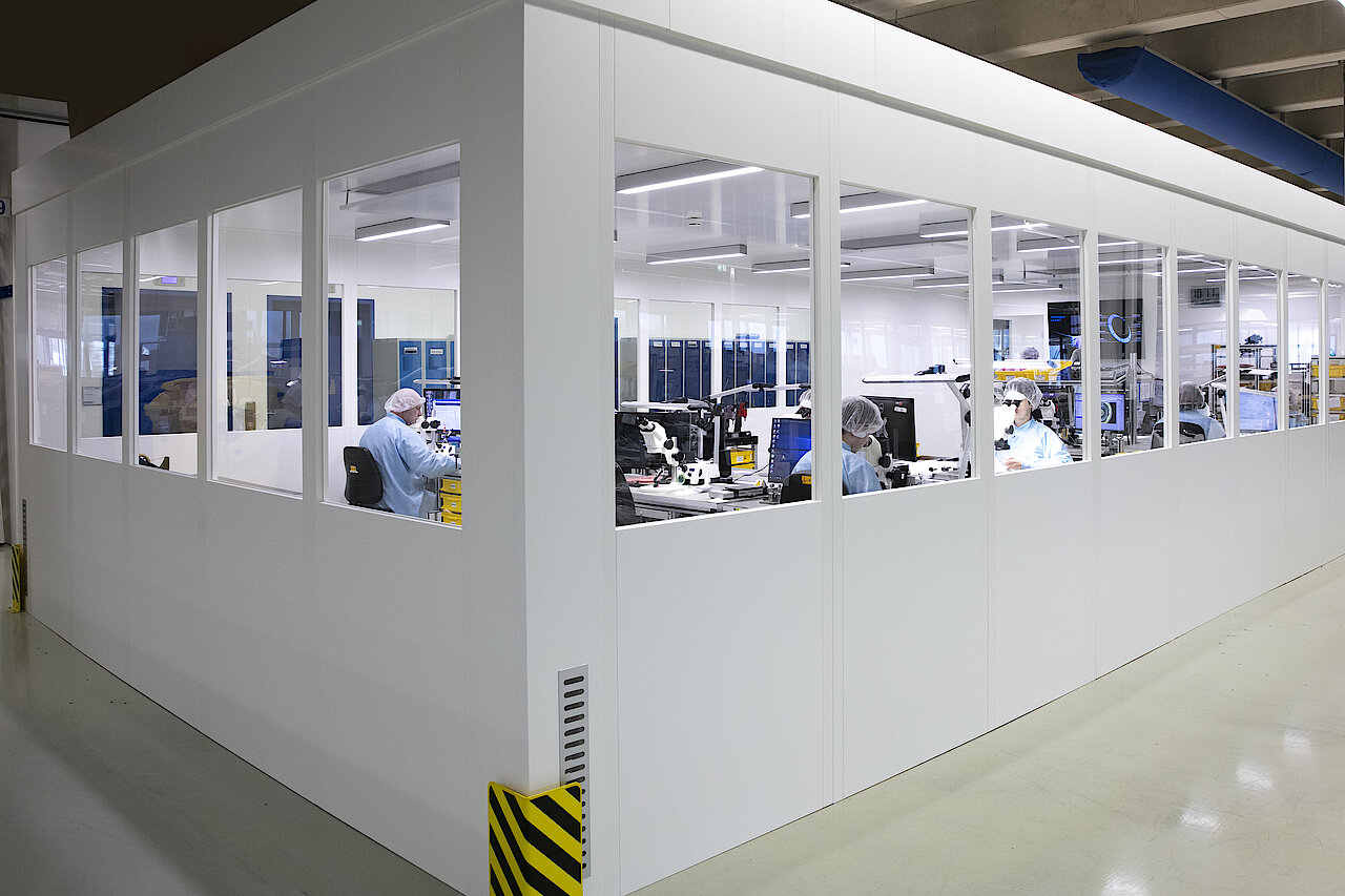 Employees work at different workstations in a clean room. 